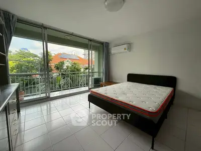 Spacious bedroom with large windows and balcony access, offering a serene garden view.
