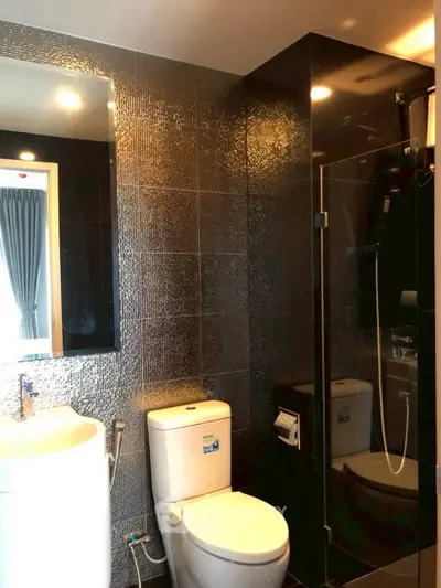 Modern bathroom with sleek black tiles and glass shower enclosure