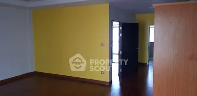 Spacious room with vibrant yellow accent wall and wooden flooring, ideal for modern living.