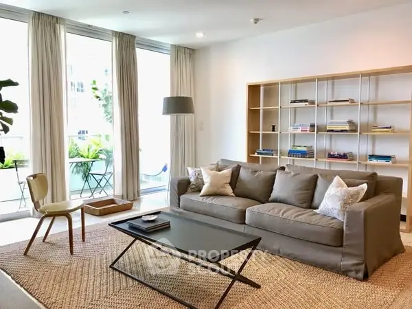 Modern living room with cozy sofa and stylish decor, featuring a large window with balcony view.