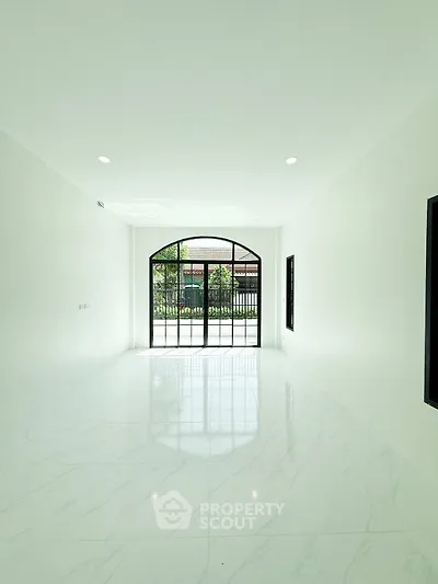 Spacious minimalist room with large window and marble flooring, perfect for modern living.