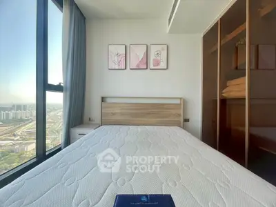 Modern bedroom with large window and city view, featuring a comfortable bed and stylish decor.