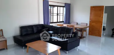 Spacious living room with modern black leather sofa and dining area, perfect for family gatherings.