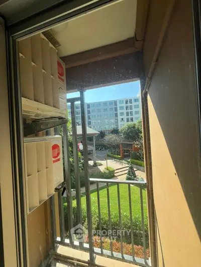 Charming balcony view overlooking lush garden and modern building facade.