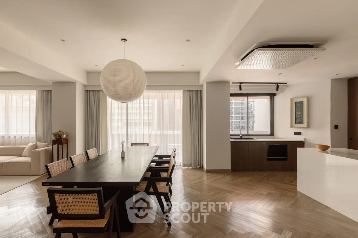 Spacious modern living room with dining area and open kitchen, featuring elegant wooden flooring and stylish decor.