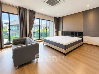 Spacious modern bedroom with large windows and elegant decor in a luxury home.