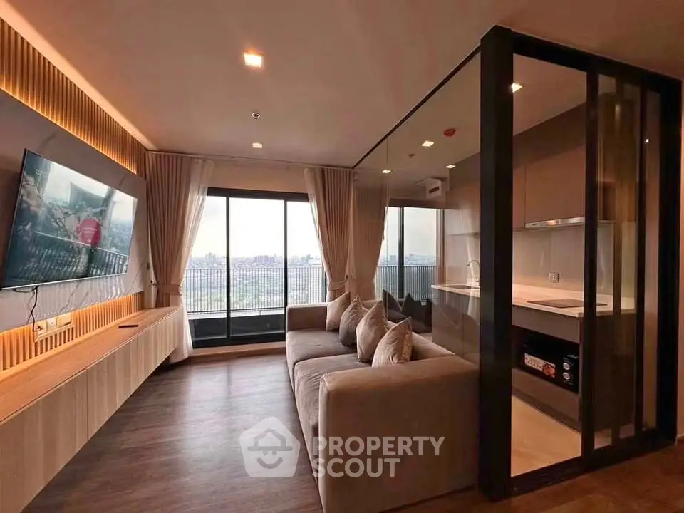 Modern living room with open kitchen and city view, featuring sleek design and cozy ambiance.