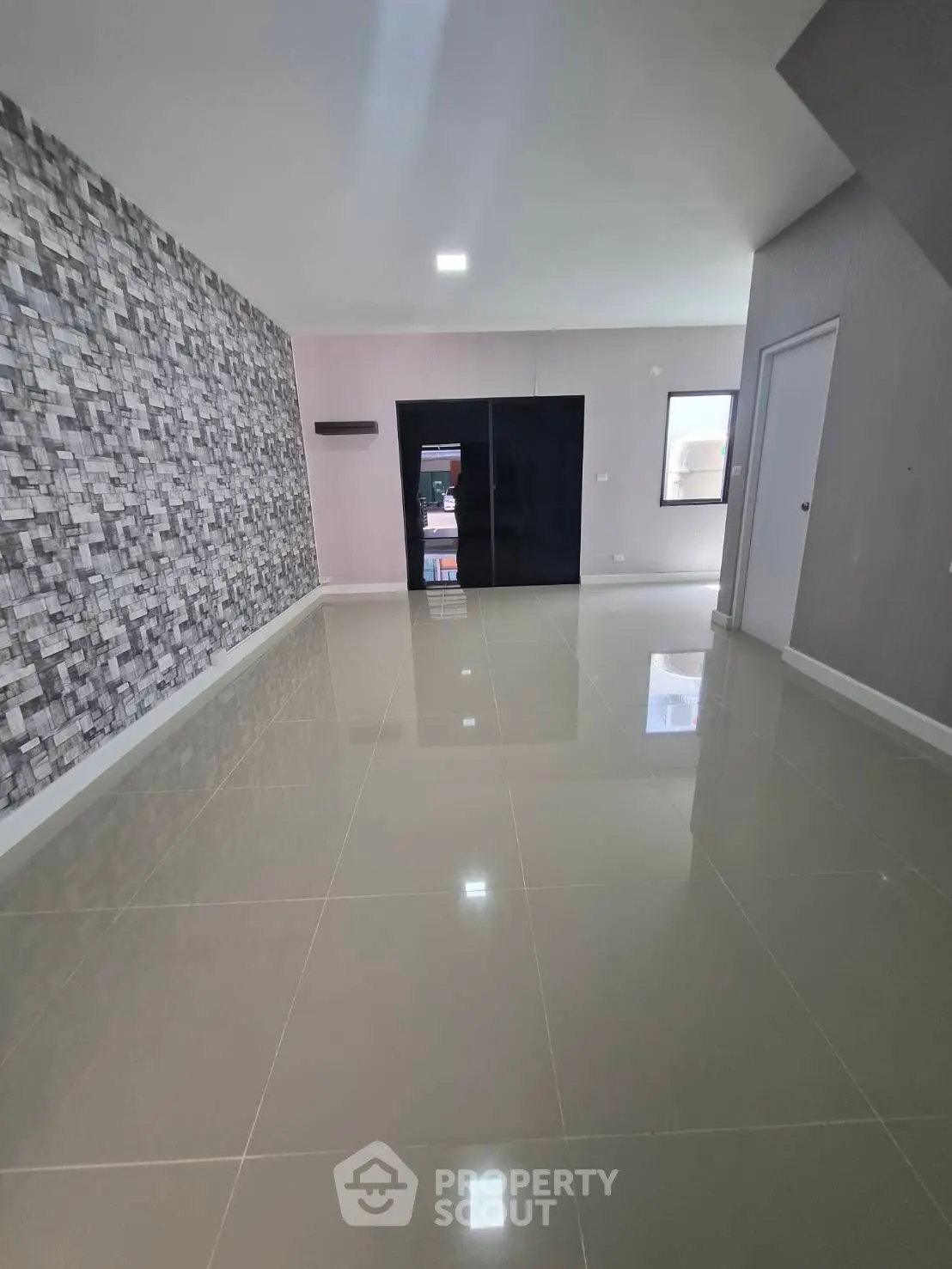 Spacious modern living room with glossy tiled floors and stylish accent wall.