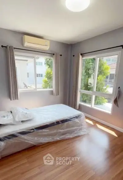 Bright bedroom with large windows and wooden flooring in modern home.