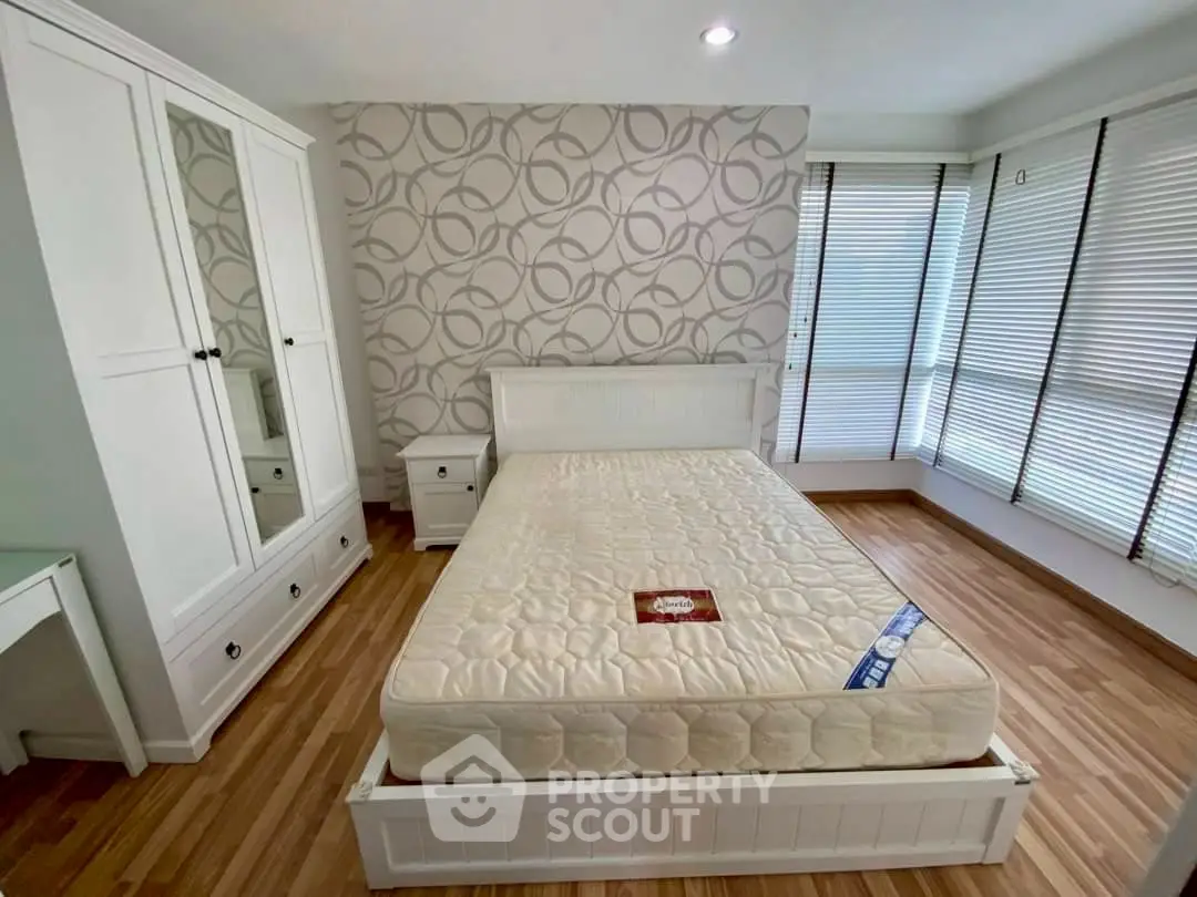 Spacious bedroom with modern decor and large windows for natural light.