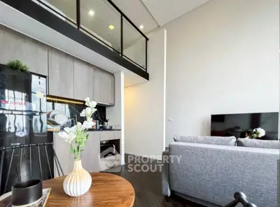 Modern loft apartment with open kitchen and stylish living area, featuring high ceilings and contemporary decor.