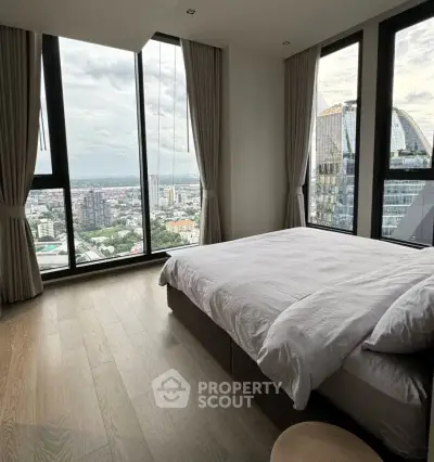 Luxurious bedroom with panoramic city views and floor-to-ceiling windows in a modern high-rise apartment.