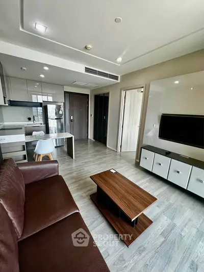 Modern living room with open kitchen, sleek furniture, and natural light in a stylish apartment.