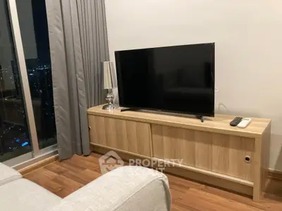 Modern living room with sleek TV setup and city view, featuring elegant wooden flooring and stylish decor.