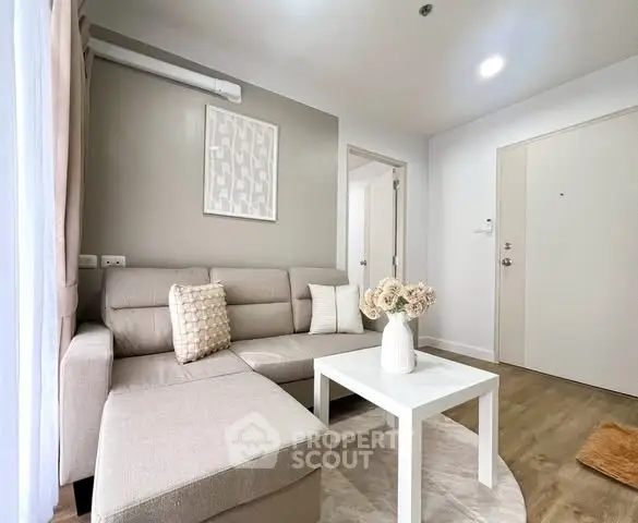 Modern living room with beige sectional sofa and white coffee table in a cozy apartment.