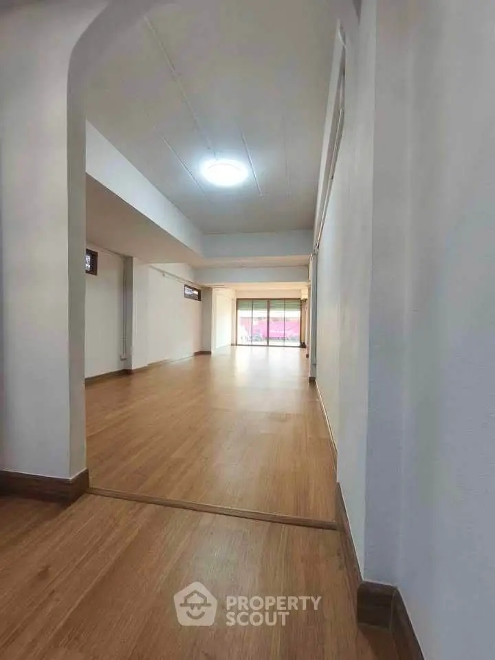 Spacious open-plan interior with wooden flooring and large windows.