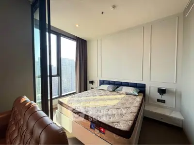 Modern bedroom with large window offering stunning city views and elegant furnishings.