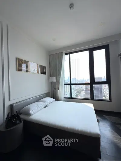 Modern bedroom with city view, featuring large window and stylish decor.