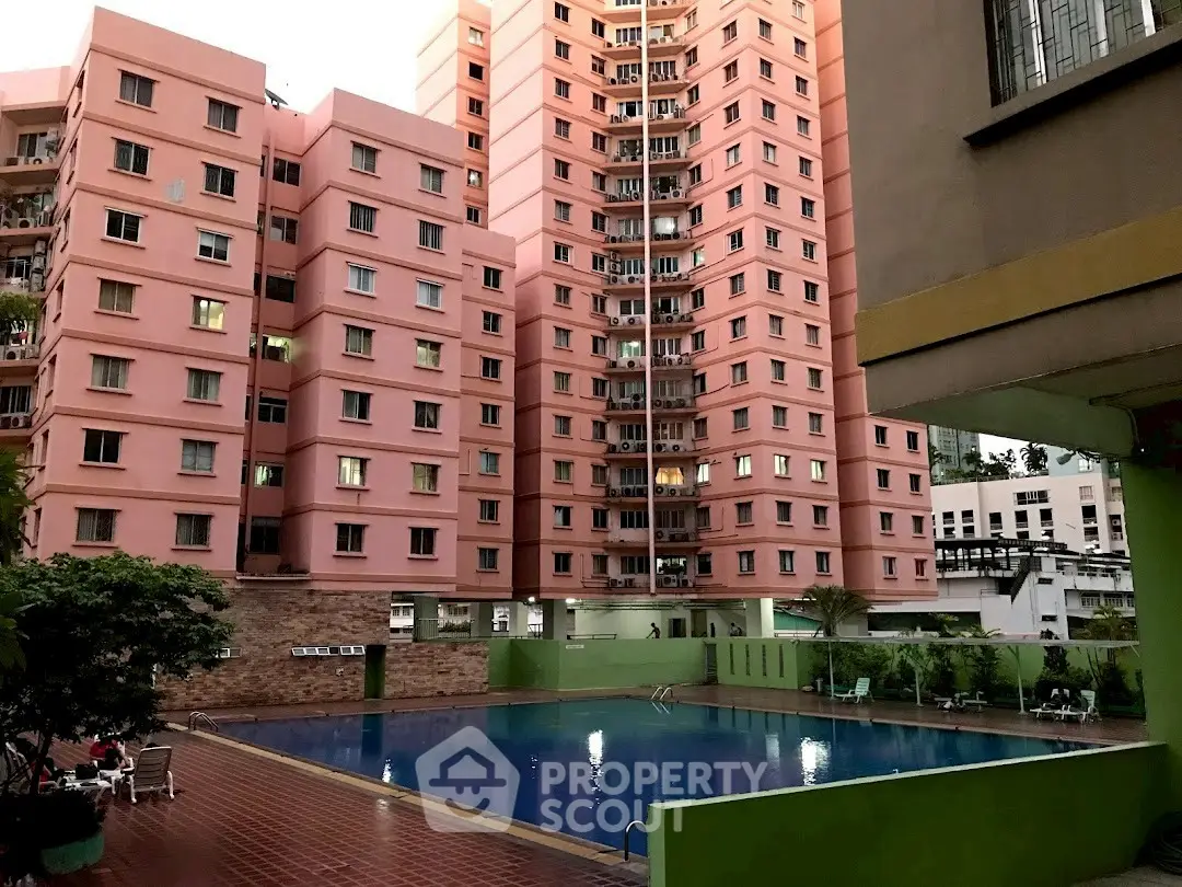 Stunning residential complex with a large swimming pool and pink high-rise buildings.