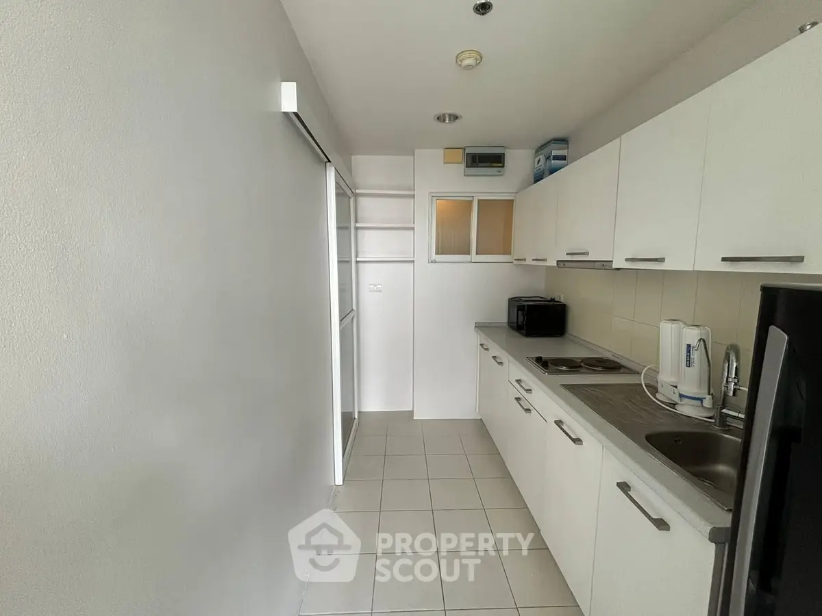 Modern kitchen with sleek white cabinets and tiled flooring in a compact layout.