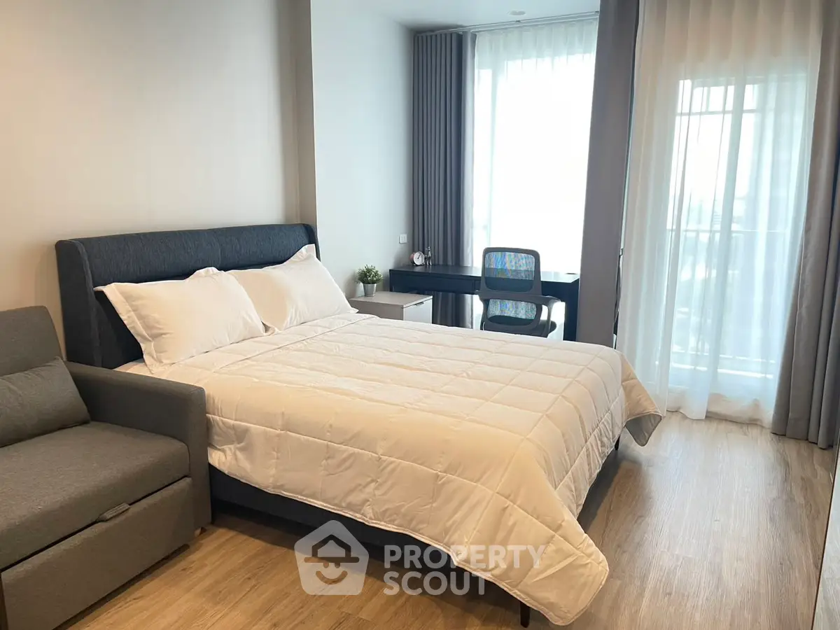 Modern bedroom with cozy bed and study area, featuring natural light and stylish decor.