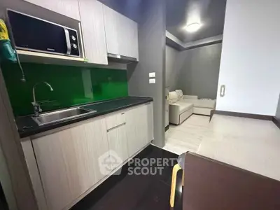 Modern kitchen with sleek cabinetry and open layout leading to cozy living area.