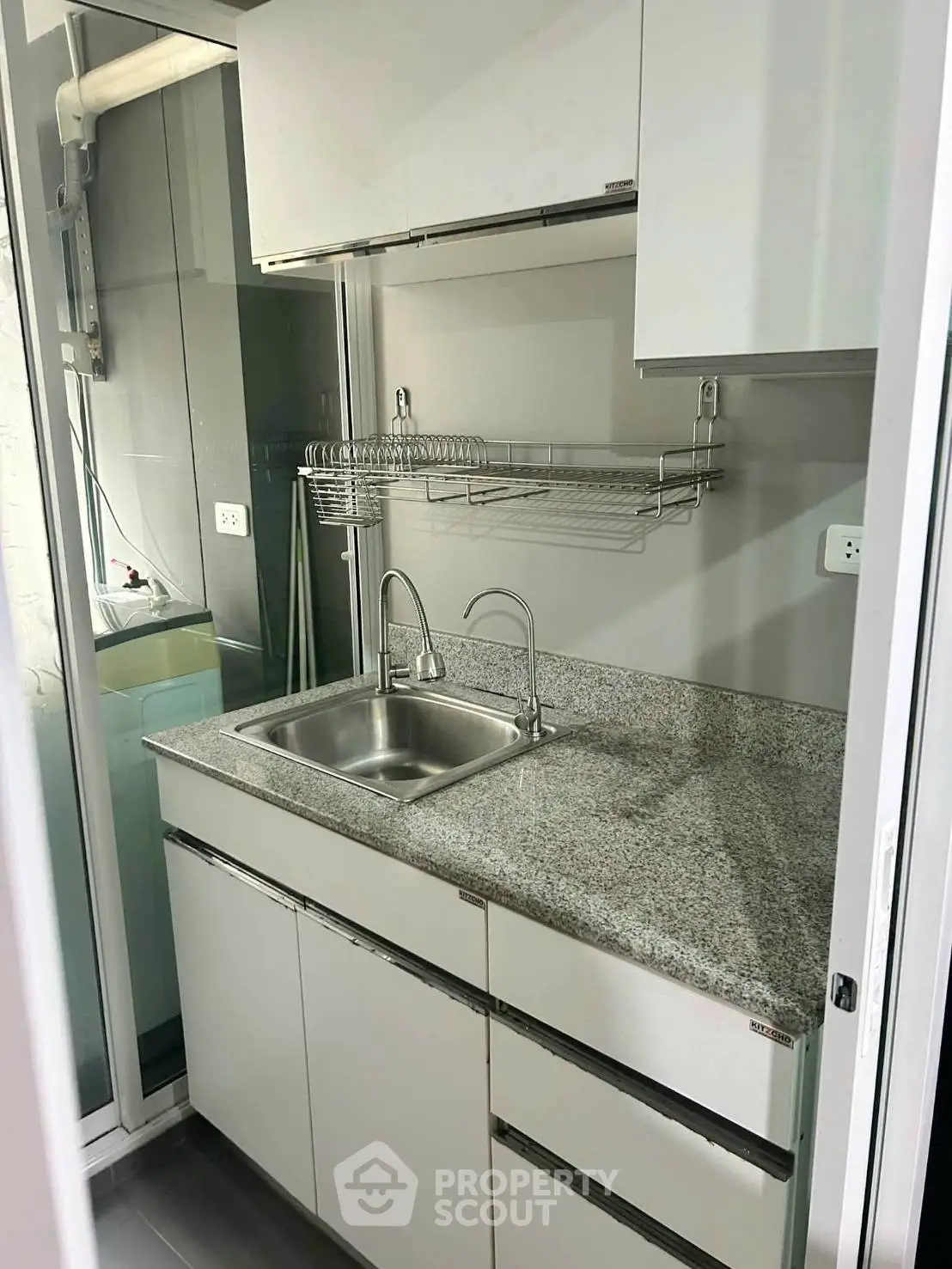 Compact modern kitchen with granite countertop and stainless steel sink in a cozy apartment.