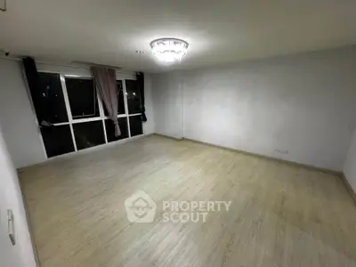 Spacious empty room with large window and elegant chandelier, perfect for customization.