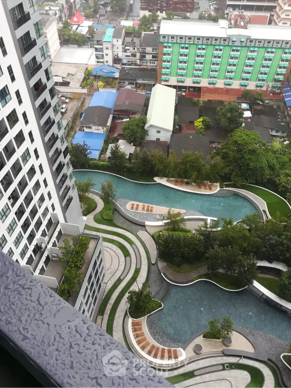 Stunning aerial view of modern residential complex with lush gardens and winding pool.