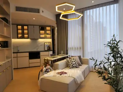 Modern living room with stylish lighting and open kitchen layout, featuring elegant decor and large windows.