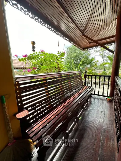 Charming wooden balcony with lush garden view, perfect for relaxation.