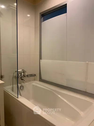 Modern bathroom with sleek bathtub and frosted glass window