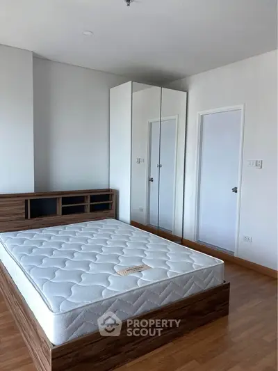 Spacious bedroom with modern wooden bed and mirrored wardrobe