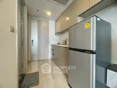 Modern kitchen with sleek cabinetry and stainless steel appliances in a compact apartment.