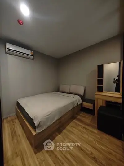 Modern bedroom with wooden flooring and air conditioning in a cozy apartment.