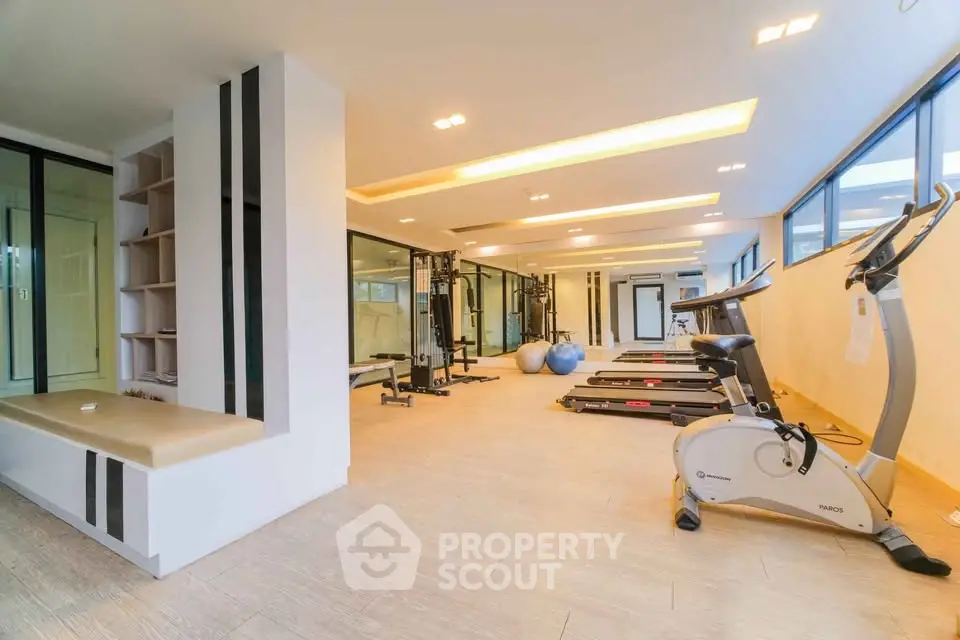 Spacious modern gym with exercise equipment and mirrored walls in luxury real estate property.