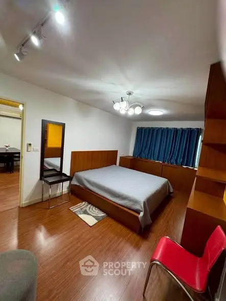 Spacious bedroom with modern lighting and wooden flooring, featuring a cozy bed and stylish decor.