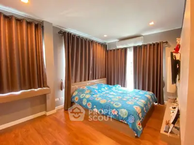 Cozy bedroom with wooden flooring and large windows for natural light