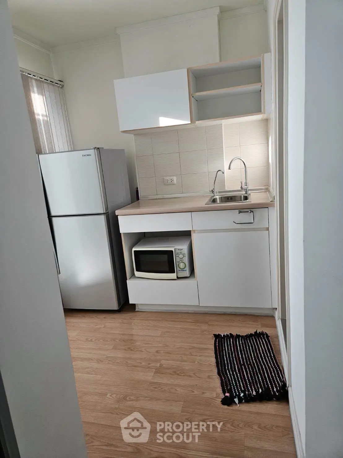 Compact kitchen with modern appliances and sleek cabinetry in a cozy apartment setting.