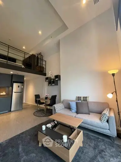 Modern loft-style living room with high ceilings and mezzanine, featuring cozy seating and stylish decor.