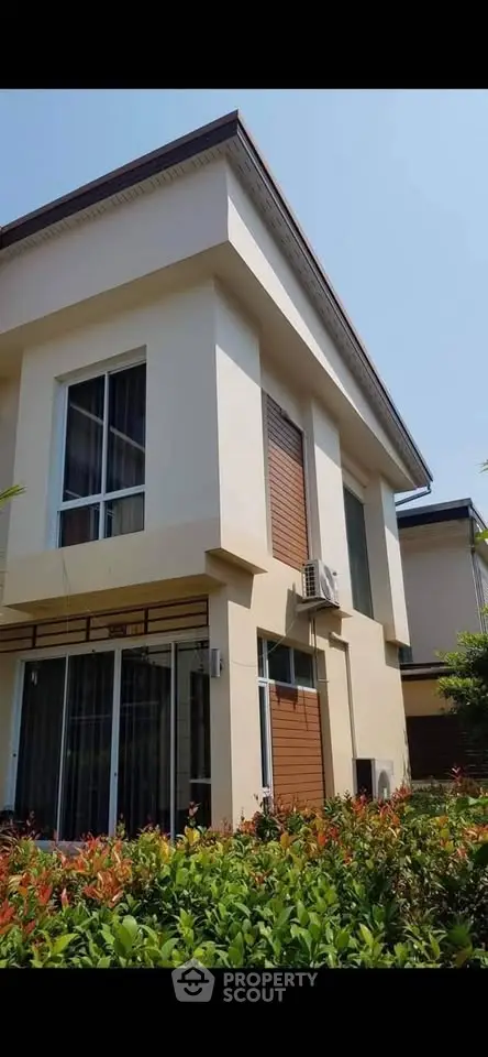 Modern two-story house with large windows and lush garden