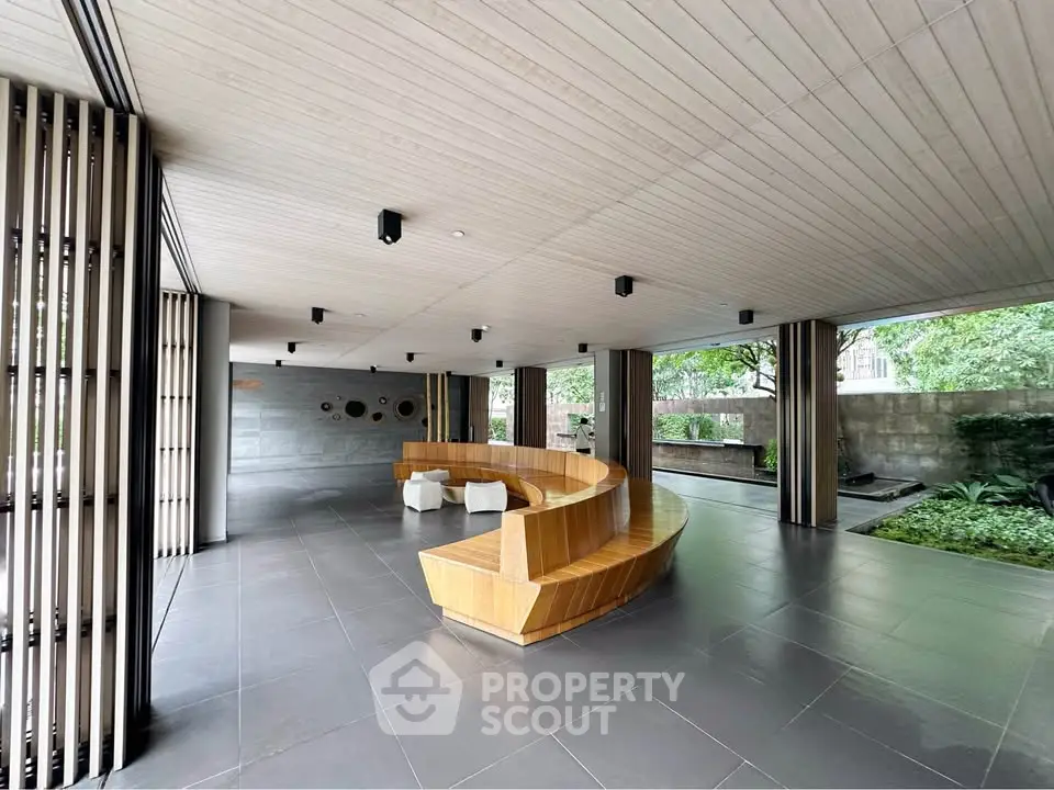 Modern building entrance with sleek wooden seating and lush greenery