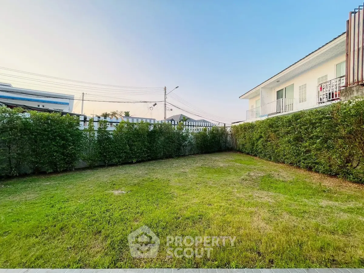 Spacious backyard with lush green lawn and modern house exterior, perfect for outdoor activities.