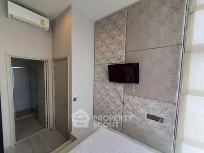 Modern bedroom with wall-mounted TV and air conditioning, featuring a sleek bathroom entrance.