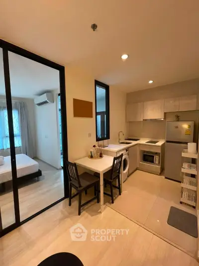 Modern apartment kitchen with dining area and view into bedroom