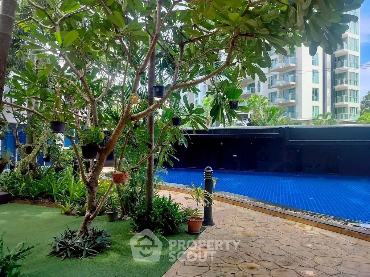 Luxurious poolside garden with lush greenery and modern apartment backdrop.