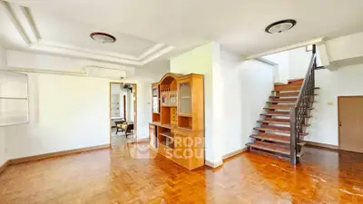 Spacious living room with wooden flooring and elegant staircase in a bright home.