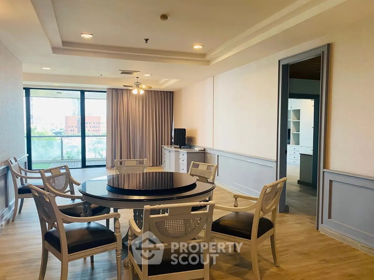 Spacious living room with elegant dining set and large windows offering natural light.