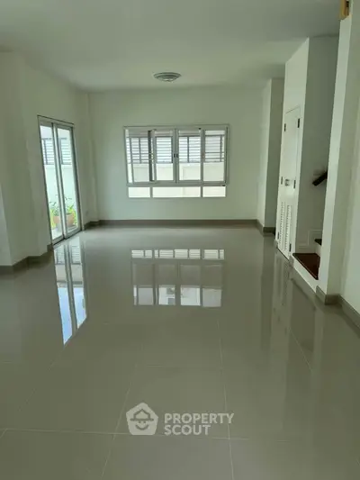 Spacious unfurnished living room with large windows and glossy tiled floors.