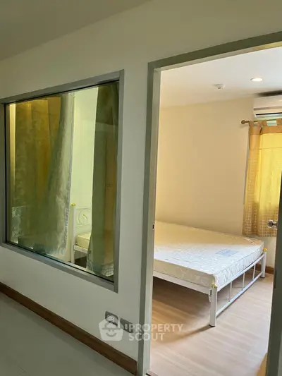 Spacious bedroom with large window and natural light, featuring modern design and air conditioning.